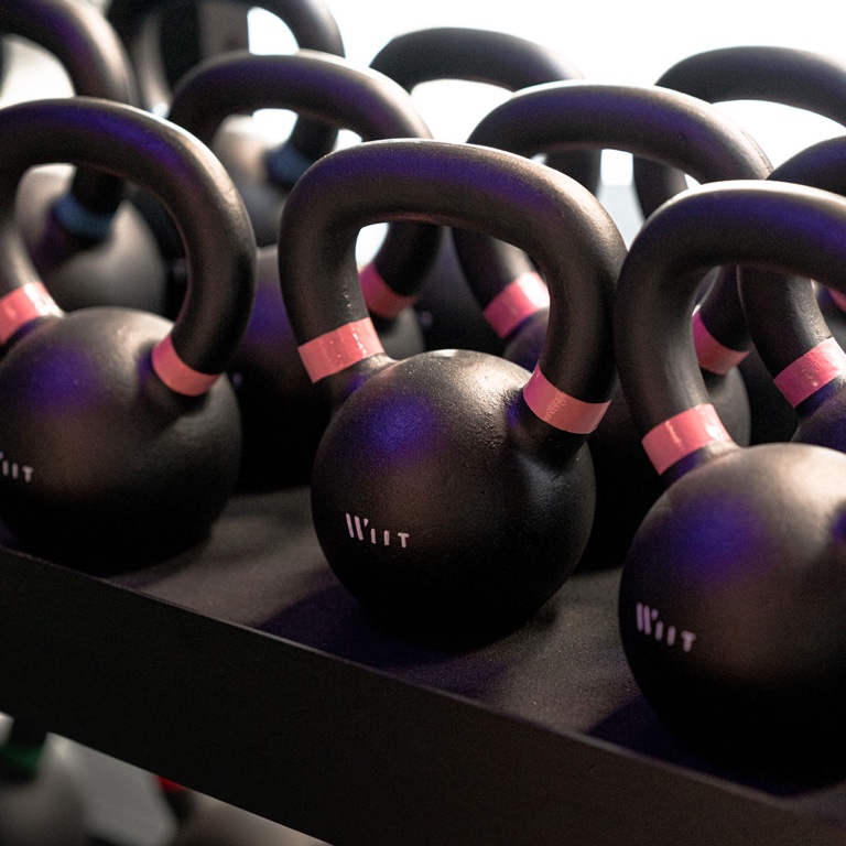 Les kettlebells rangées par charge le long du mur.