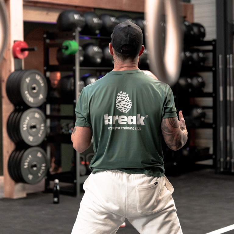 Un adhérent de dos, t-shirt Break, devant le rack de barres.