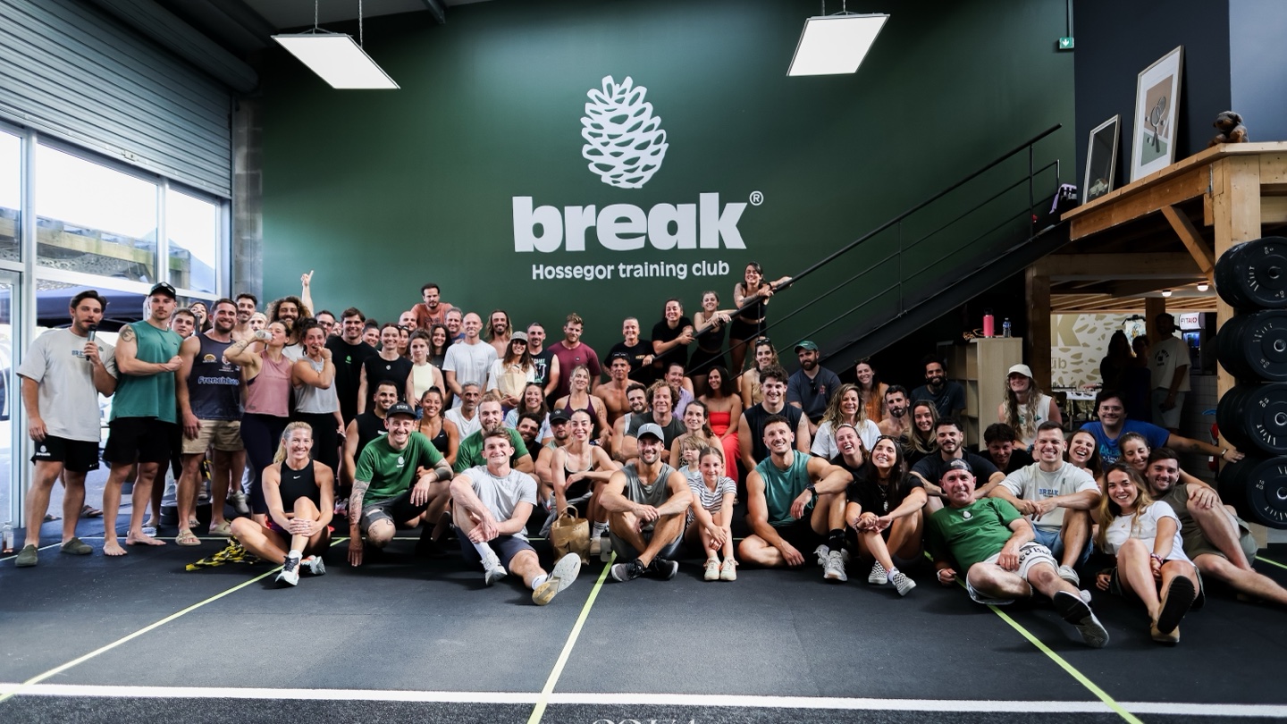 La communauté Break réunie dans la salle, devant le mur vert au logo à la pomme de pin.